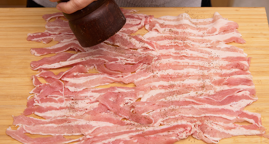 写真 豚バラ肉を広げ、表面に塩こしょうをふる。