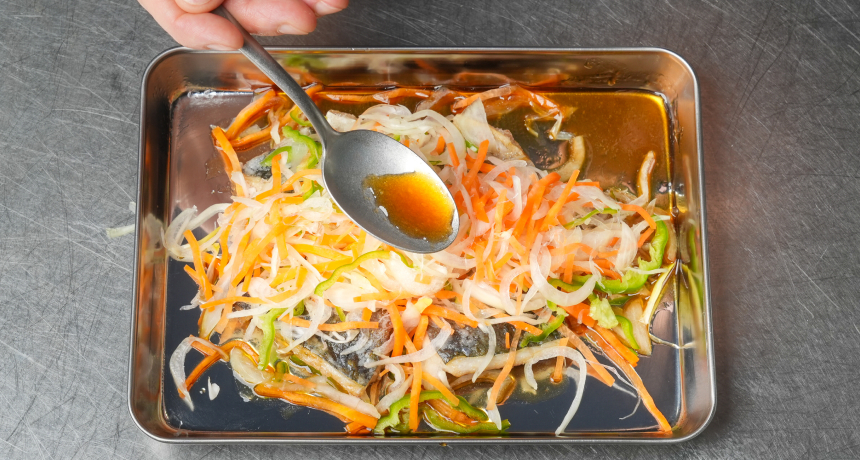 写真 ①の野菜の水気を切り、⑤の鯵の上にのせる。南蛮漬けのたれをスプーンで回しかける。