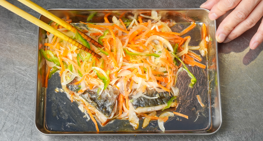 写真 時々、鯵と野菜の上下をひっくり返すようにしてしばらく置き、味をなじませる。味がしみ込んだら、器に盛り付ける。