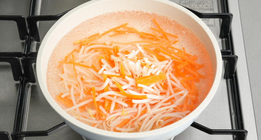写真 鍋にたっぷりのお湯を沸かし、もやし・にんじんを茹でて水にさらす。